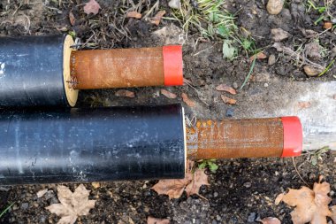 Topraktaki siyah borular ve kum. Şehirdeki kanalizasyon borularının kurulumu. Kapat.