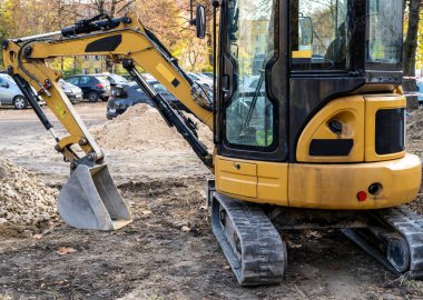 İşte küçük bir buldozer. Turuncu kazıcı yolda. Şehirdeki inşaat işleri..