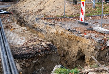 Topraktaki siyah borular ve kum. Şehirdeki kanalizasyon borularının kurulumu