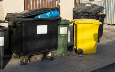 Siyah, mavi, sarı, yeşil çöp geri dönüşüm kutuları. Atıkları ayır, çevre kavramını koru. Atıkları ayır, çöpleri ayır. Kağıt, cam, plastik renkli çöp tenekeleri.