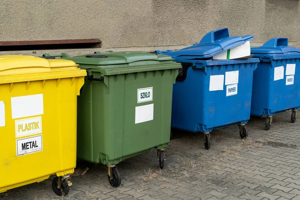 stock image Black, blue, yellow, green garbage recycling bins on street in city. Separate waste, preserve the environment concept. Segregate waste, sorting garbage. Colored trash cans with paper, glass, plastic