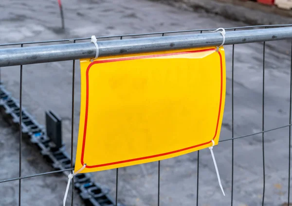 yellow sign on the metal fence