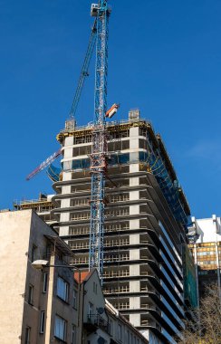 Mavi gökyüzüne karşı vinçleri olan bir inşaat alanı. Endüstriyel geçmiş. Modern gökdelenler. Tamamlanmamış yapı