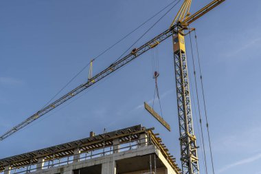 Mavi gökyüzüne karşı vinçleri olan bir inşaat alanı. Endüstriyel geçmiş. Modern gökdelenler. Tamamlanmamış yapı