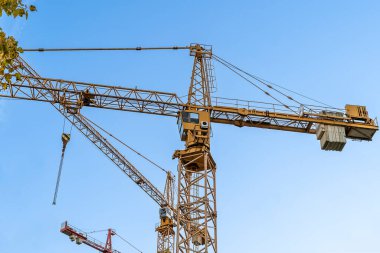Mavi gökyüzüne karşı sarı vinçleri olan bir inşaat alanı. Endüstriyel geçmiş. Modern gökdelenler. Tamamlanmamış yapı