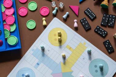 Different desktop games, figures, dices, parts on the brown table. Home entertaiment, indoor games