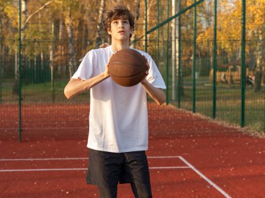 Sahada top oynayan tişörtlü hoş bir genç kız. Stadyumda koşan bir genç. Spor, hobi, erkekler için aktif yaşam tarzı