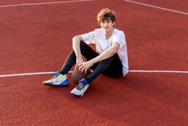 Sahada top oynayan tişörtlü hoş bir genç kız. Stadyumda koşan bir genç. Spor, hobi, erkekler için aktif yaşam tarzı