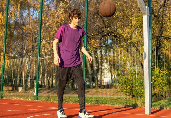 Sahada top oynayan tişörtlü hoş bir genç kız. Stadyumda koşan bir genç. Spor, hobi, erkekler için aktif yaşam tarzı