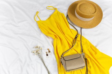 Straw hat and yellow summer dress on the white background. Spring, summer collection of women's clothing, accessories. Casual outfit