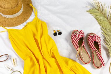 Straw hat and yellow summer dress on the white background. Spring, summer collection of women's clothing, accessories. Casual outfit