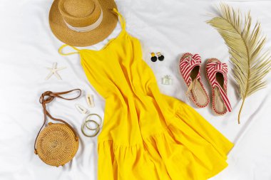 Straw hat and yellow summer dress on the white background. Spring, summer collection of women's clothing, accessories. Casual outfit