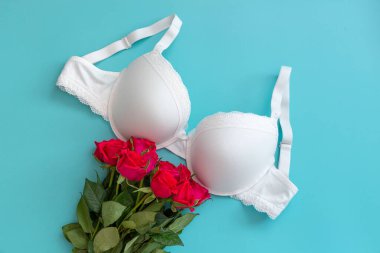 Top view white lace lingerie with red roses on green background. Set of woman essential underwear or accessory. Flat lay, beauty blog or social media minimal concept. Present for Valentines day