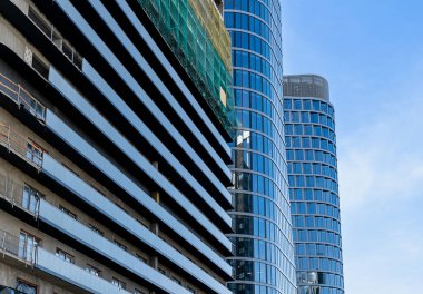 Mavi gökyüzüne karşı vinçleri olan bir inşaat alanı. Endüstriyel geçmiş. Modern gökdelenler. Tamamlanmamış yapı