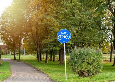 Parkta bisikletli mavi tabela. Şehirde özel bisiklet yolu. Şehir geçmişi. Kapatın. Yaz, bahar aktiviteleri. Yeni yaşam tarzı için bisikletler