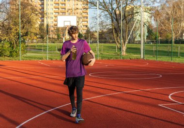 Sahada top oynayan tişörtlü hoş bir genç kız. Stadyumda koşan bir genç. Spor, hobi, erkekler için aktif yaşam tarzı
