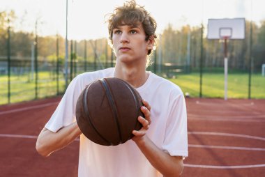 Sahada top oynayan tişörtlü hoş bir genç kız. Stadyumda koşan bir genç. Spor, hobi, erkekler için aktif yaşam tarzı