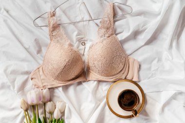 Yatağın üzerinde yumuşak pembe dantel sütyen. Kadınlar yumuşak iç çamaşırları, iç çamaşırları. Üst Manzara, kapat. Düz yatak, güzellik blogu ya da sosyal medya minimum konsepti. Sevgililer Günü, Kadınlar Günü hediyesi.