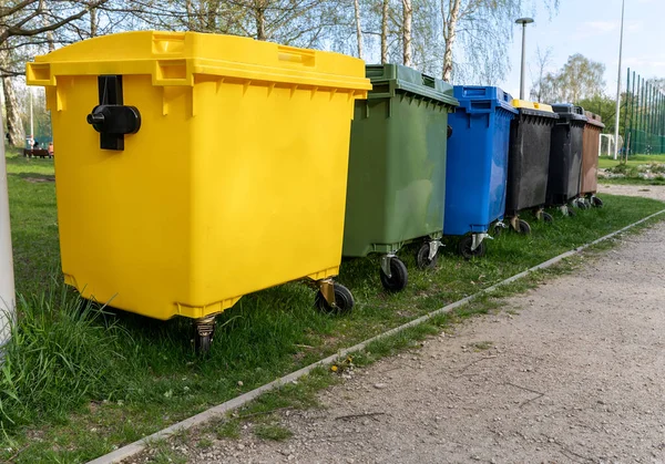 Black, blue, yellow, green garbage recycling bins on street in city. Separate waste, recycling environment concept. Segregate waste, sorting garbage. Colored trash cans with paper, glass, plastic