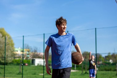 Sahada basketbol oynayan bir çocuk. Stadyumda koşan bir genç. Spor, hobi, erkekler için aktif yaşam tarzı