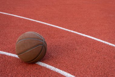 Basketbol topu yere düştü. Kırmızı sahada yakın çekim topu. Sokakta ya da kapalı sahada basketbol. İnsansız spor malzemeleri. Minimalizm. Şablon, spor arka planı