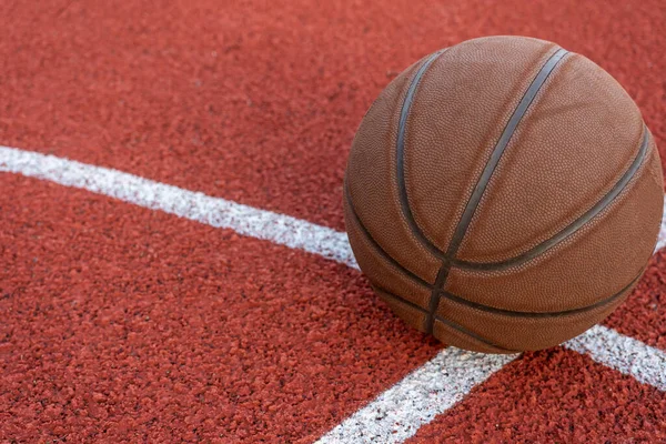 Basketbol topu yere düştü. Kırmızı sahada yakın çekim topu. Sokakta ya da kapalı sahada basketbol. İnsansız spor malzemeleri. Minimalizm. Şablon, spor arka planı