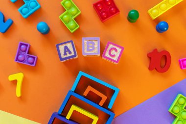 Ahşap çocuk oyuncakları renkli kağıtlar üzerinde. Eğitici oyuncak blokları, piramit, kalemler, numaralar. Anaokulu, anaokulu ya da kreş için oyuncaklar. Uzayı metin için kopyala. Üst görünüm