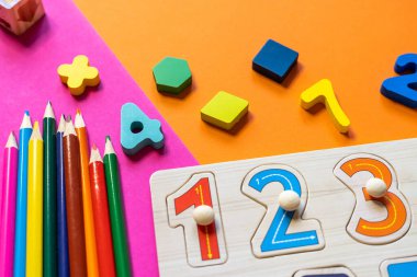 Ahşap çocuk oyuncakları renkli kağıtlar üzerinde. Eğitici oyuncak blokları, piramit, kalemler, numaralar. Anaokulu, anaokulu ya da kreş için oyuncaklar. Uzayı metin için kopyala. Üst görünüm