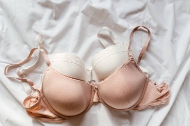 Yatağın üzerinde yumuşak, beyaz dantel sütyen. Kadınlar yumuşak iç çamaşırları, iç çamaşırları. Üst Manzara, kapat. Düz yatak, güzellik blogu ya da sosyal medya minimum konsepti. Sevgililer Günü, Kadınlar Günü hediyesi.