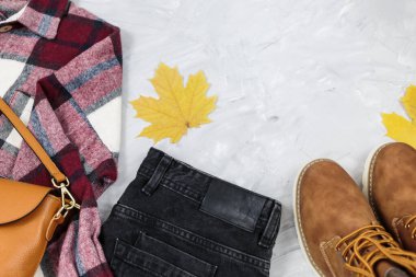 Güz yaprakları, spor ayakkabıları, kot pantolon, gri masadaki kareli gömlek. Moda Sonbahar aksesuarları.