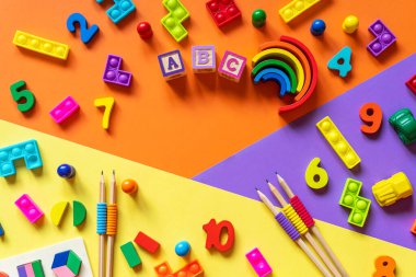 Ahşap çocuk oyuncakları renkli kağıtlar üzerinde. Eğitici oyuncak blokları, piramit, kalemler, numaralar. Anaokulu, anaokulu ya da kreş için oyuncaklar. Uzayı metin için kopyala. Üst görünüm