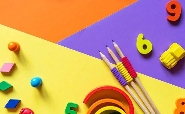 stock image Wooden kids toys on colourful paper. Educational toys blocks, pyramid, pencils, numbers. Toys for kindergarten, preschool or daycare. Copy space for text. Top view