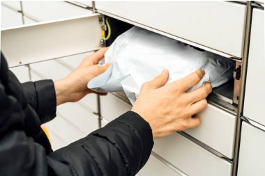 Posta terminalinin yanında elinde kutu olan bir adam. Paket teslimat makinesi. Elinde bir karton kutu tutan kişi. Posta ve posta servisi, online alışveriş, e-ticaret konsepti