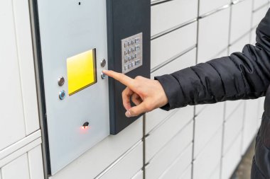 A man with a box in his hands near the self-service mail terminal. Parcel delivery machine. Person holding a cardboard box. Mail delivery and post service, online shopping, e commerce concept clipart