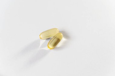 Beyaz arkaplandaki sarı kapsülleri kapat. Kapsüllerde Omega 3 yağı. Tıbbi, vitaminler, sağlık geçmişi