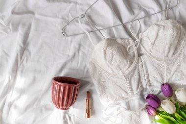 Yatağın üzerinde yumuşak, beyaz dantel sütyen. Kadınlar yumuşak iç çamaşırları, iç çamaşırları. Üst Manzara, kapat. Düz yatak, güzellik blogu ya da sosyal medya minimum konsepti. Sevgililer Günü, Kadınlar Günü hediyesi.