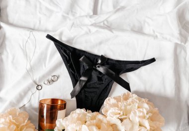 Yatağın üzerinde yumuşak siyah pantolon. Kadınlar yumuşak donlar, iç çamaşırları, iç çamaşırları. Üst Manzara, kapat. Düz yatak, güzellik blogu ya da sosyal medya minimum konsepti. Sevgililer Günü, Kadınlar Günü hediyesi.