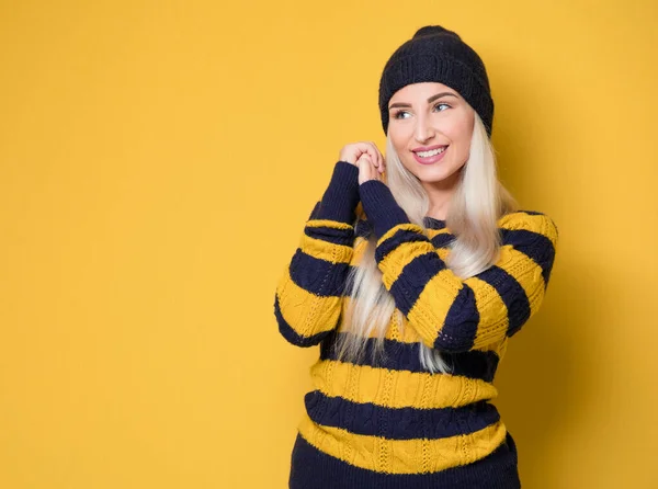 喜びの少女の肖像画 笑顔の表情で幸せな若い女性は モデルはウールキャップとセーターを着て 黄色の背景に隔離された スタジオショット — ストック写真