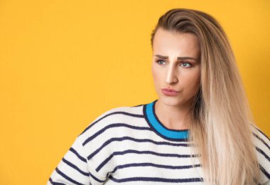 Dudakları büzüşmüş genç bir kadın, düşünürken sorgulanıyor, kız yukarı bakıyor ve ilhama ihtiyacı var, sarı arka planda izole edilmiş. Stüdyo çekimi