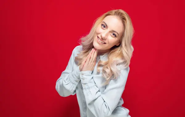 ハッピーな若い女性は 手のひらを閉じている間 赤い背景に隔離された笑顔の表情を持つ幸せな女性 スタジオショット ストック画像