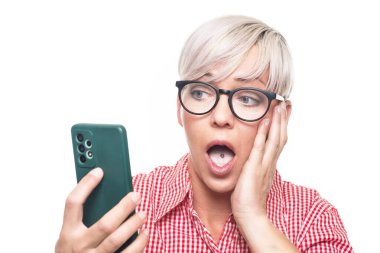 Beyaz arka planda izole edilmiş, cep telefonu olan korkmuş yetişkin bir kadın. Şok olmuş orta yaşlı kadın elinde akıllı telefon tutuyor. - İnanılmaz. Stüdyo çekimi