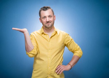 Ürününüz için avucunda sarı gömlekli, mavi arka planda bedava reklam alanı olan bir adam. Stüdyo çekimi