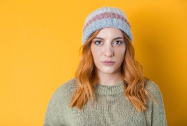 Sarı arka planda izole edilmiş, ciddi genç bir kadının kafa ve omuzları. Ön manzara. Boş yüzlü güzel bir kızın portresi. Stüdyo çekimi