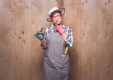 Kararlar. Bahçıvan kadının elinde budama makası vardı. Düşünceli bir kadın çiftçinin portresi. Stüdyoda ahşap arka planda kafa karışıklığı ifadesi var. Stüdyo çekimi