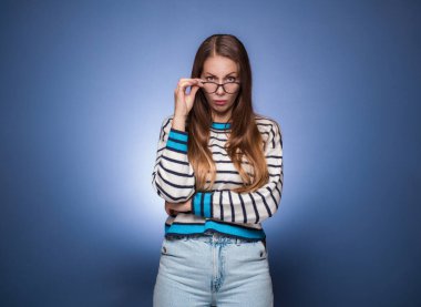 Mavi arka planda soyutlanmış, sana bakan otoriter bir kadın. Kaşlarını çatmış, kıskanç bir kız. Stüdyo çekimi