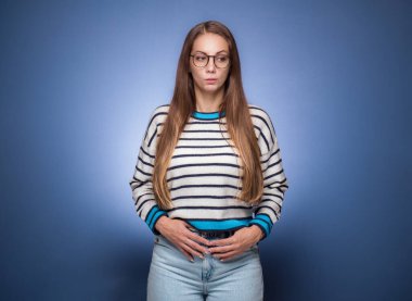 Şüphe, kadın düşüncesi. Mavi arka planda soyutlanmış, kafası karışmış, düşünceli bir kızın portresi. Stüdyo çekimi