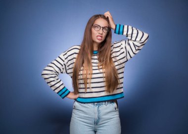 Unutkan kadın kafasını kaşıyor, mavi arka planda soyutlanmış. Hatırlatma konsepti. Stüdyo çekimi