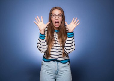 Şaşırmış bir kadın sana bakıyor, mavi arka planda soyutlanmış. Çıldırmış kız. Stüdyo çekimi