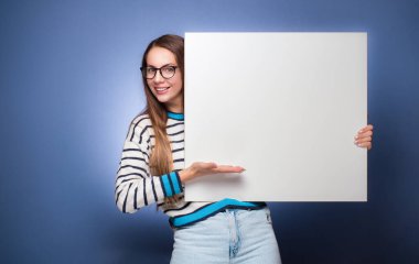 Mavi arka planda beyaz tahta tutan mutlu genç kadınlar. Boş ilan panosu ve mesaj için boş yer gösteren güzel bir kız. Stüdyo çekimi