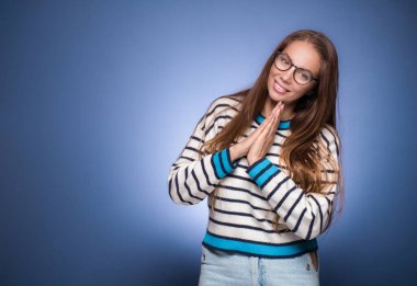 Ne olur! Dua eden kadın elini bir dua jestinde tutar, bir şey için yalvarır, mavi arka planda izole bir şekilde. Uzayı kopyala Bağışlayıcı kavram. Stüdyo çekimi